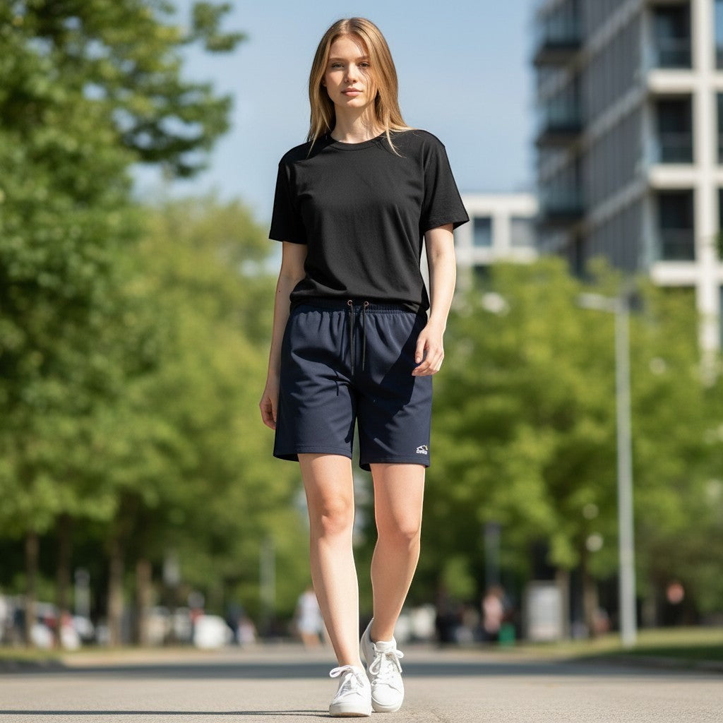 Swift Gear navy athletic performance shorts with drawstring elastic waistband and side pockets. Model is wearing a black t-shirt and white sneakers.